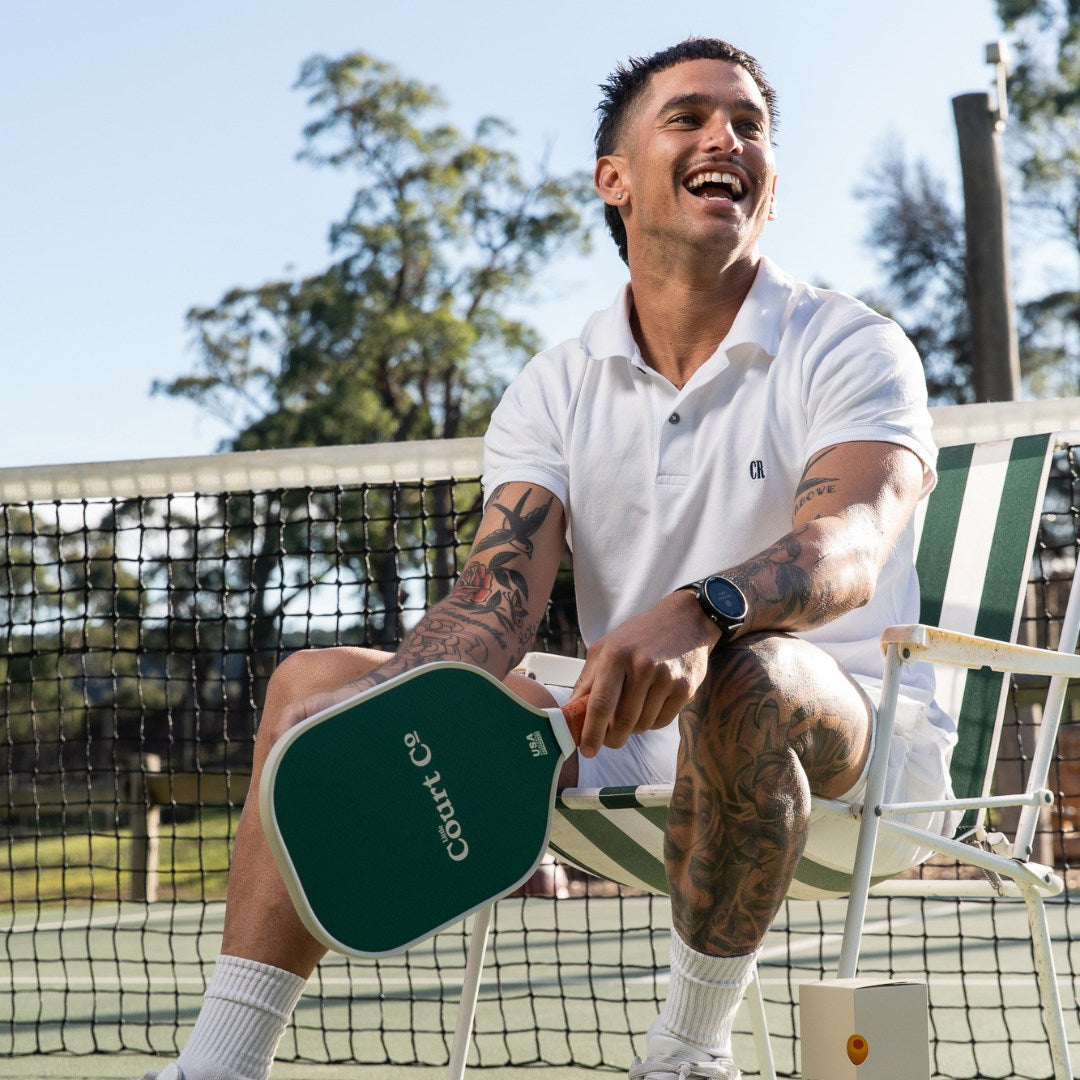 Man sitting on a chair holding a pickleball paddle