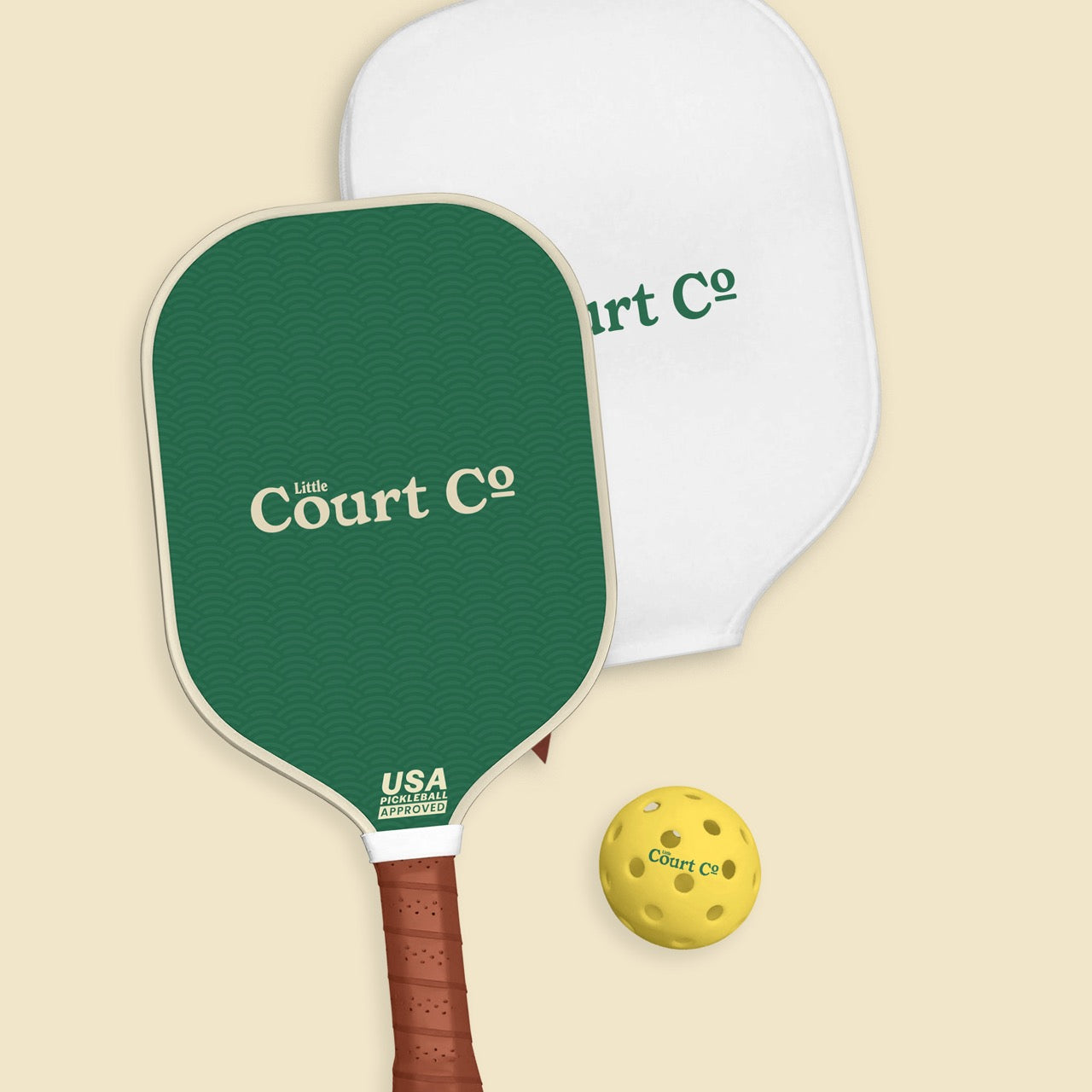 One pickleball paddles and a ball with 'Little Court Co' branding on a beige background